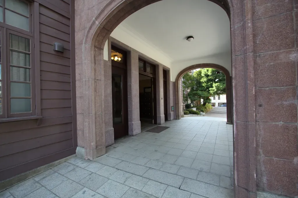 石造風の車寄(ポーチ)に御影石の階段は各式を重んずる様式に使われる構成。楕円形のアーチを潜ると壁と天井が漆喰でシンプルに仕上げられています。その効果で玄関ドアがより重厚に感じます。