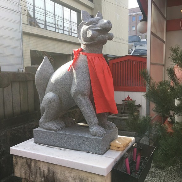 Stone inari with incense and fried tofu at its feet