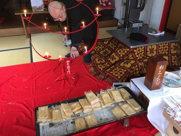 The priest fixing the candles before the altar with a piles fried tofu in front