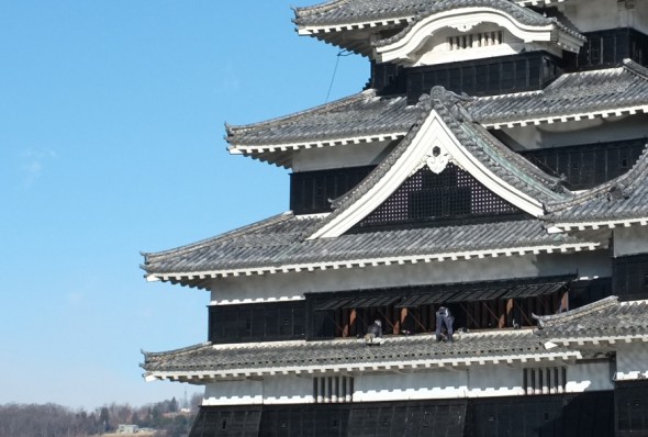Workers wiping off the roof tiles of the castle tower